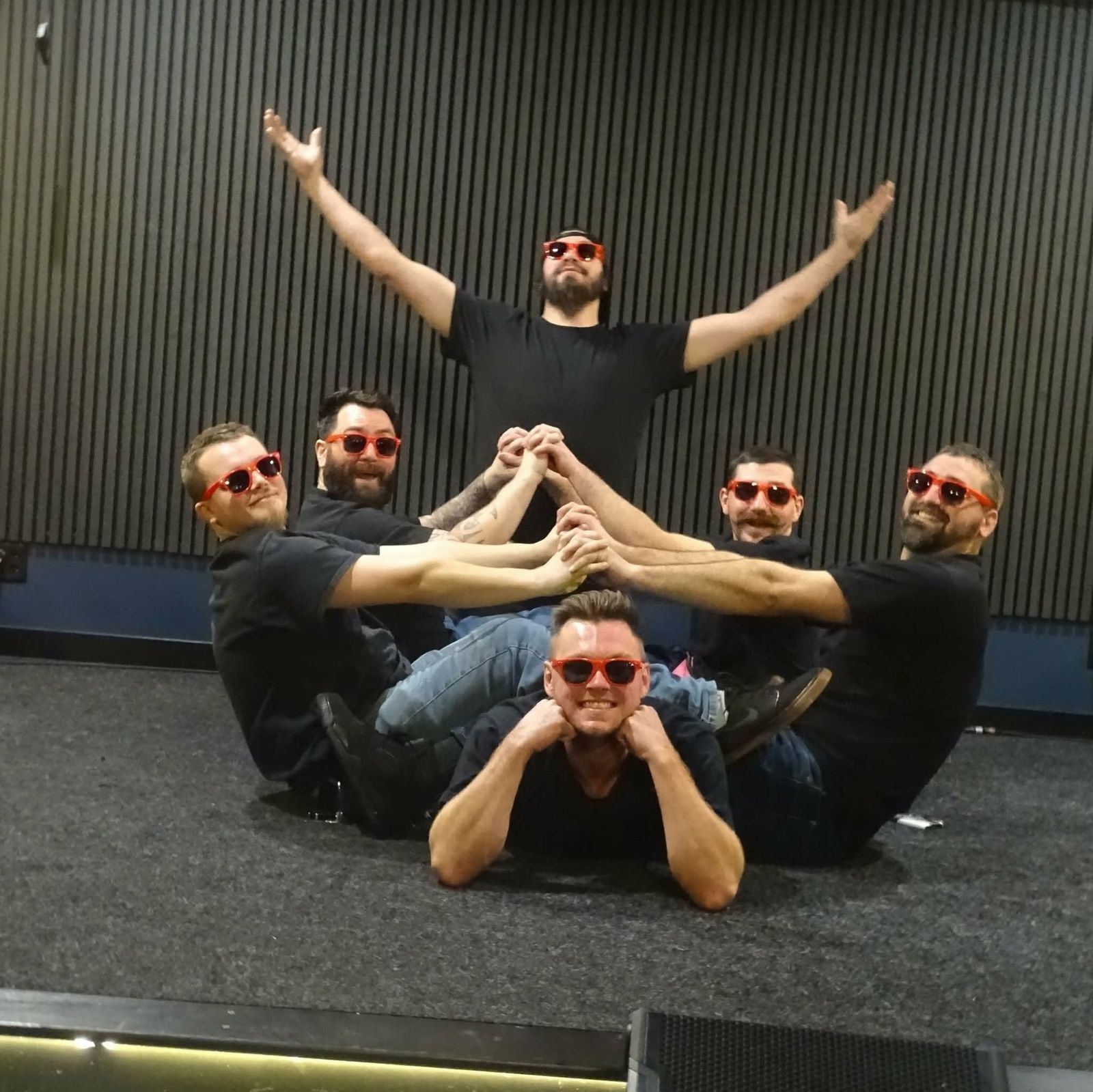 A band in matching red sunglasses posing on the stage