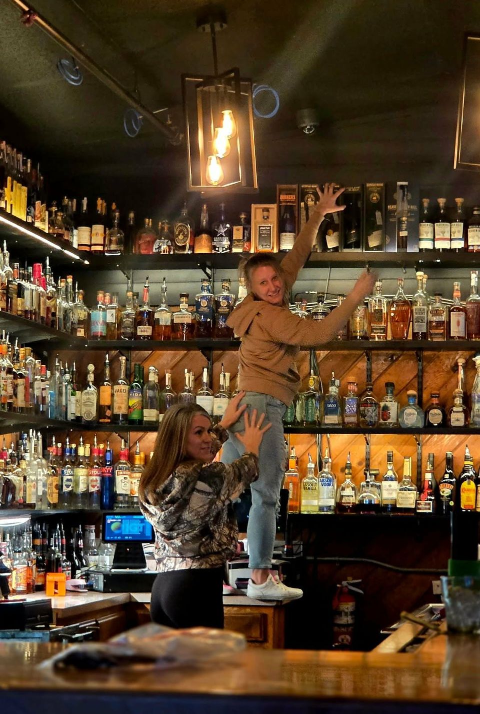 Two bartenders goofing around on the back bar